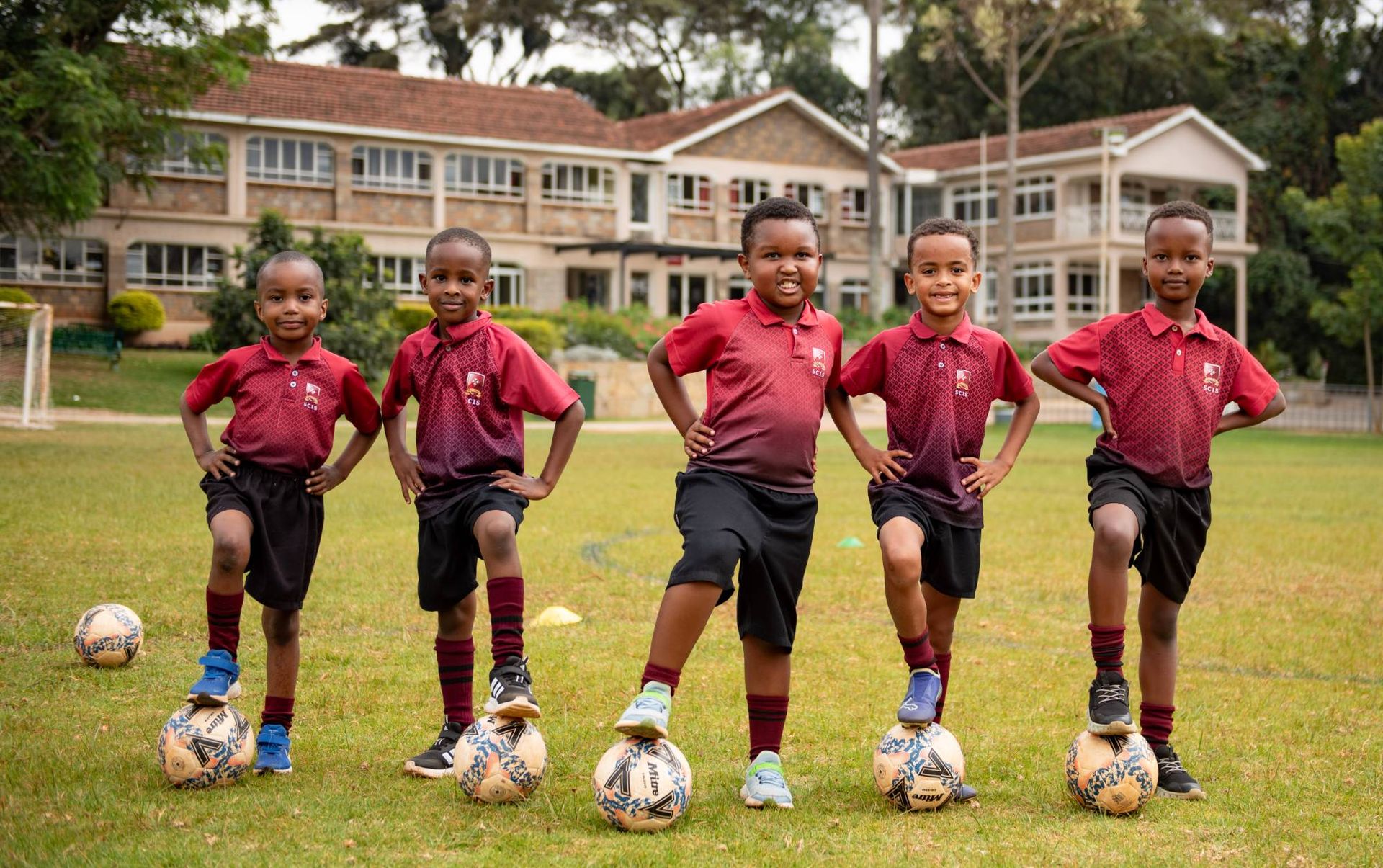 Young pupils with footballs on the school field at St. Christopher's International School