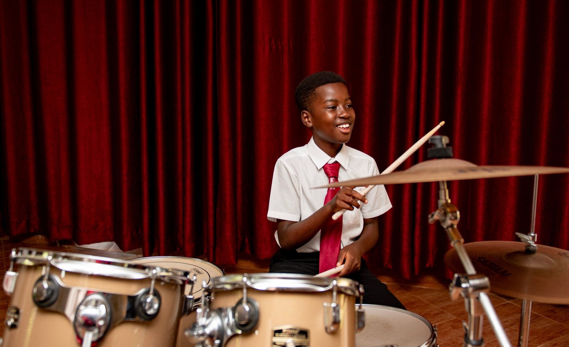 A St. Christopher's International School student playing the drums at a school performance